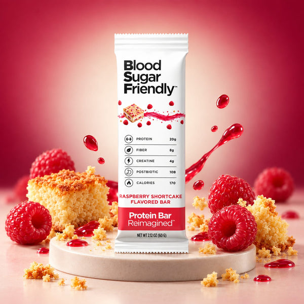 Protein Bar Reimagined™ Raspberry Shortcake bar on a round pedestal with raspberries and shortcake crumbs